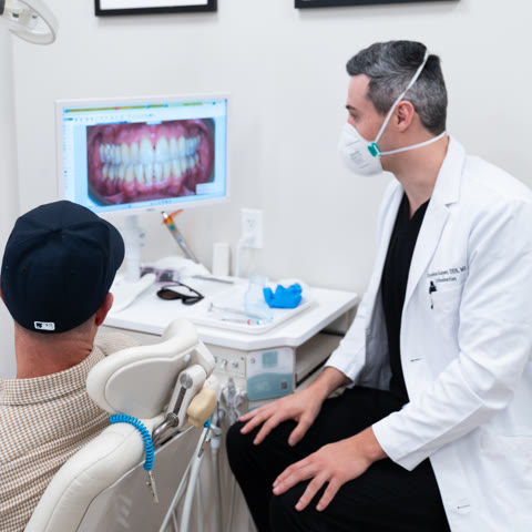 An orthodontist reviewing a patient’s smile photo with them on screen
