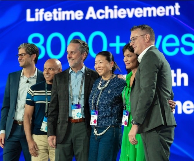 Dr. Bella Shen Garnett on stage receiving a Lifetime Achievement award for 8,000+ lives changed