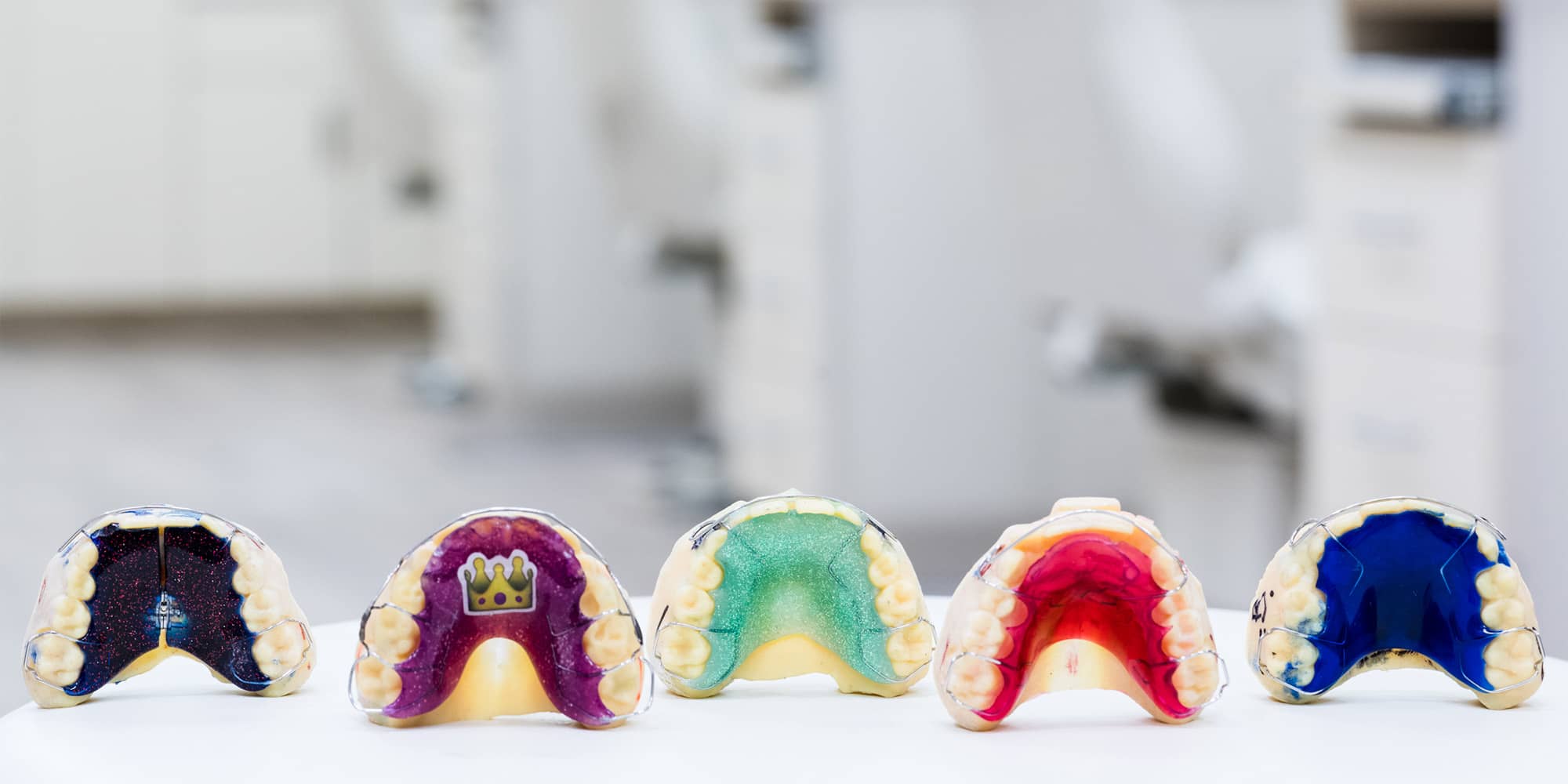 Five colourful custom-designed Hawley retainers lined up on a table